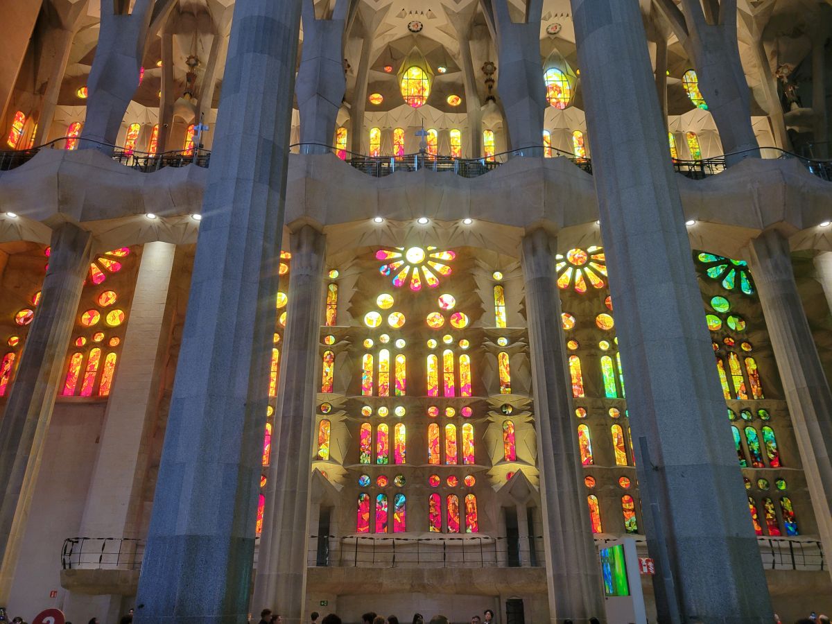 Interior of the Sagrada Família with soaring columns and warm amber and pink stained glass windows