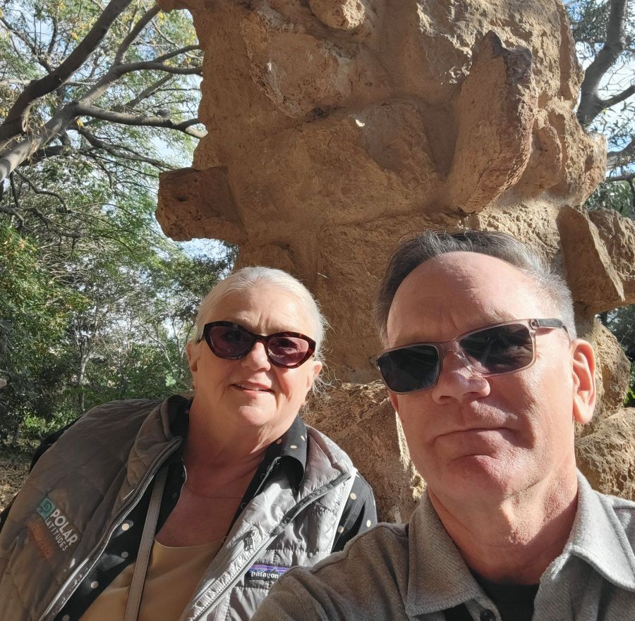 Keith and Shirley selfie in front of a large rock formation at Park Güell, Barcelona