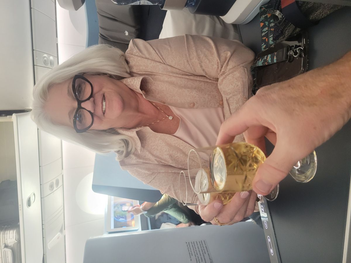 Shirley toasting with a glass of champagne in business class on the flight from Los Angeles to Barcelona
