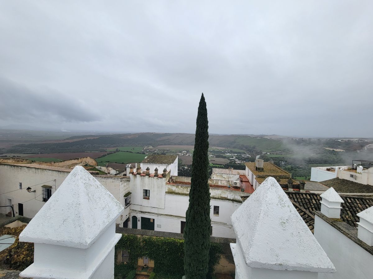 View over the white rooftops of Arcos de la Frontera and the green valley below, seen from the Parador in the rain