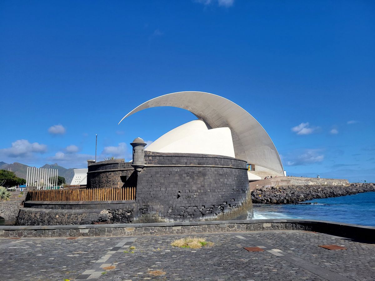 The wave-shaped Auditorio de Tenerife rising behind the dark stone Castillo de San Juan Bautista on the Santa Cruz waterfront