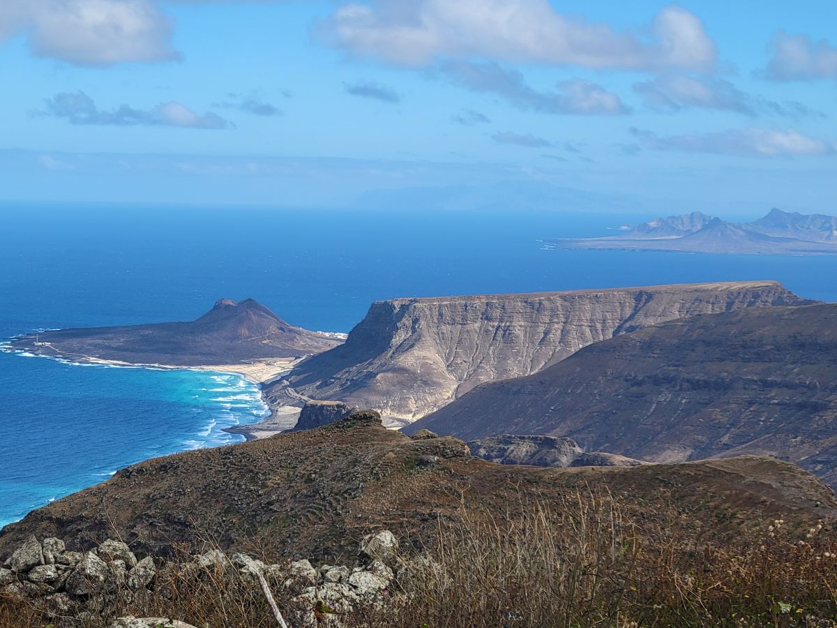 The rugged volcanic coastline of São Vicente, Cape Verde — sea cliffs, a long sandy beach, and deep blue Atlantic stretching to the horizon