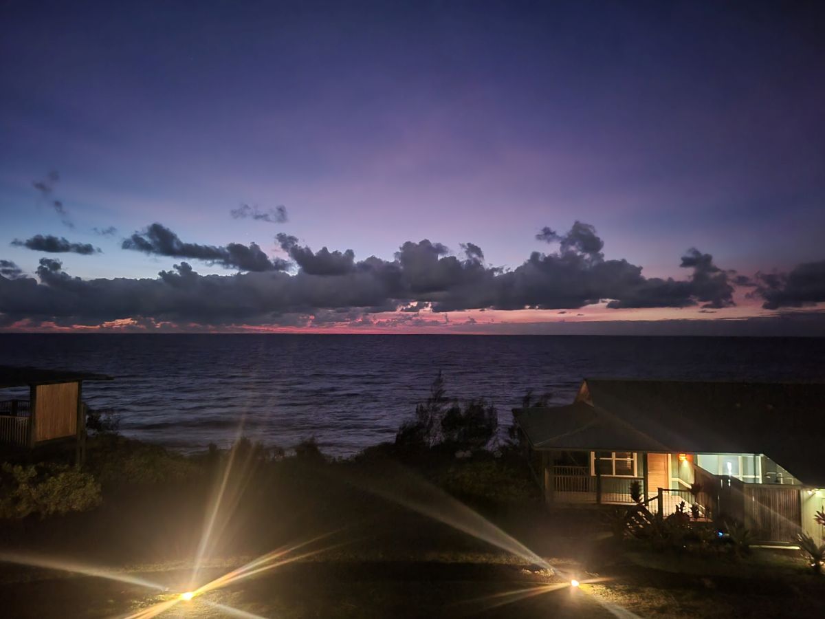 Deep purple pre-dawn sky over the ocean with resort bungalows lit in the foreground, Hana-Maui Resort