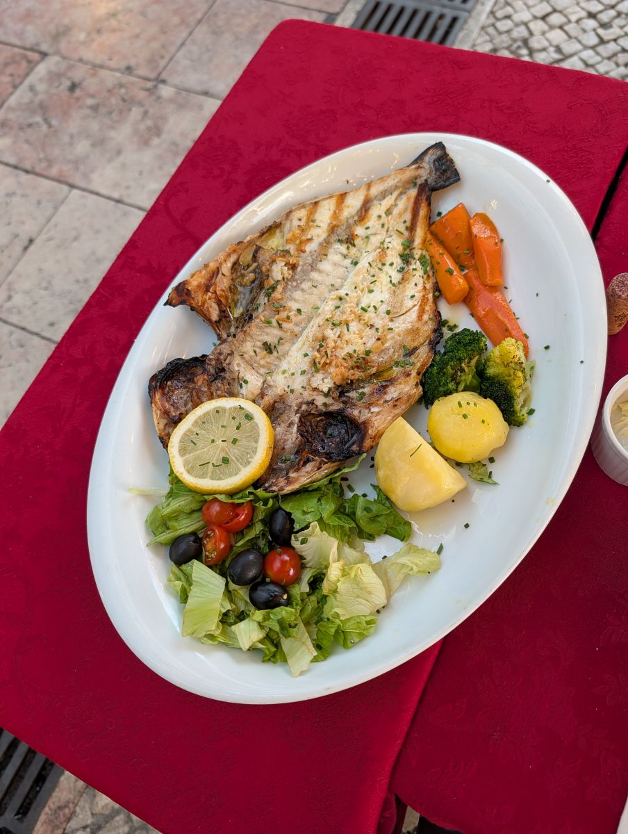 Grilled fish with vegetables and salad at an outdoor Lisbon restaurant