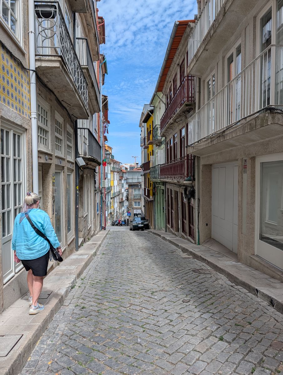 Shirley walking up a narrow cobblestone street in Porto's old town